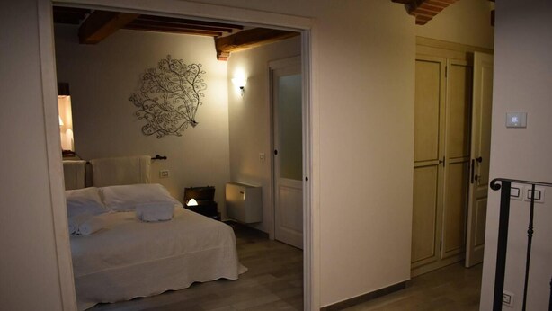 Een slaapkamer met een bed, nachtkastje, lamp en een decoratie aan de muur.