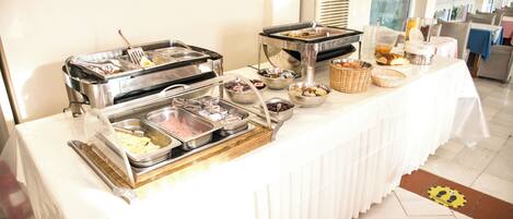 A buffet table with various food items and serving utensils.