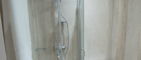 A modern bathroom with a glass-enclosed shower, a toilet, and a towel hanging on the wall.