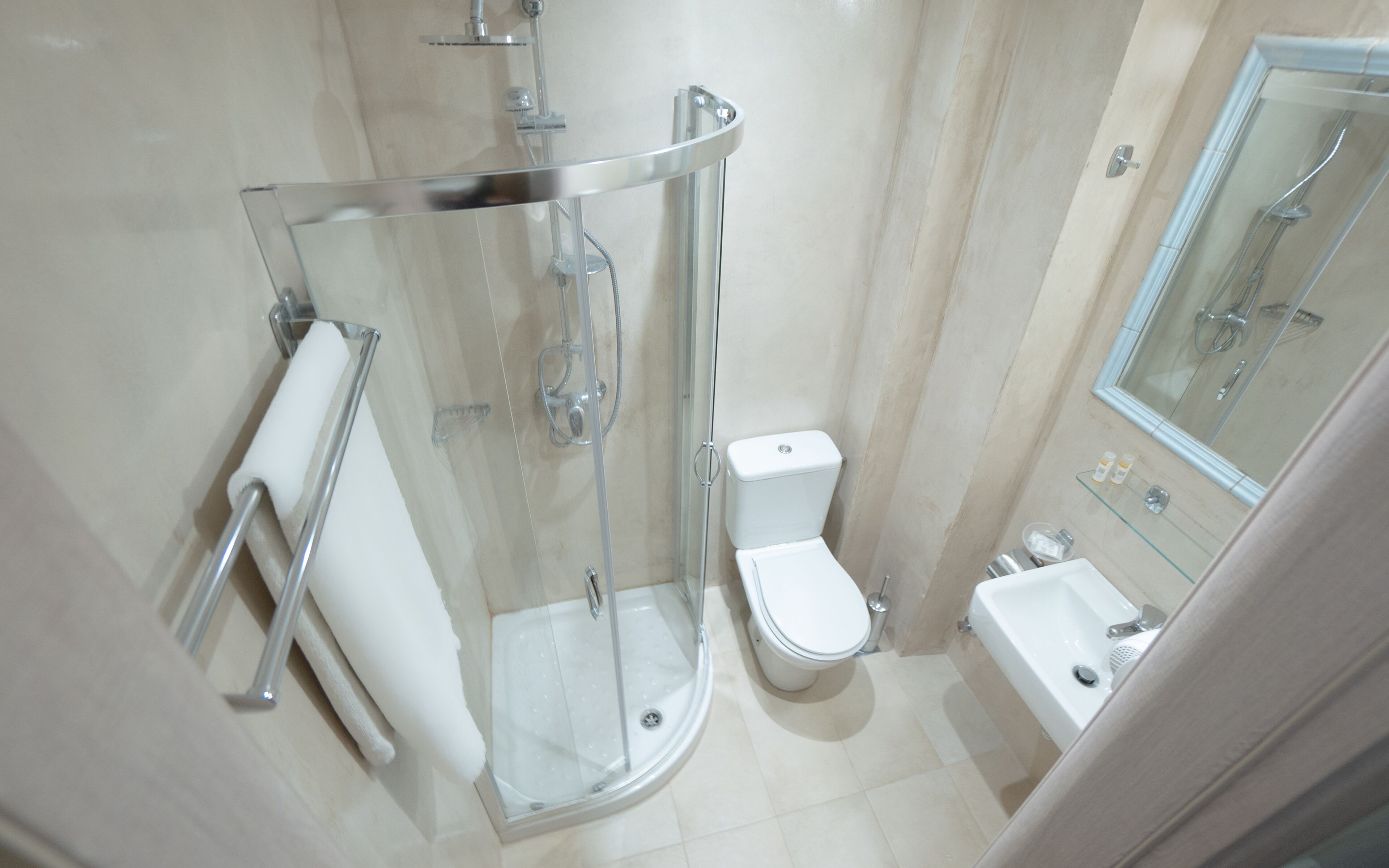 A modern bathroom with a glass-enclosed shower, a toilet, and a sink.
