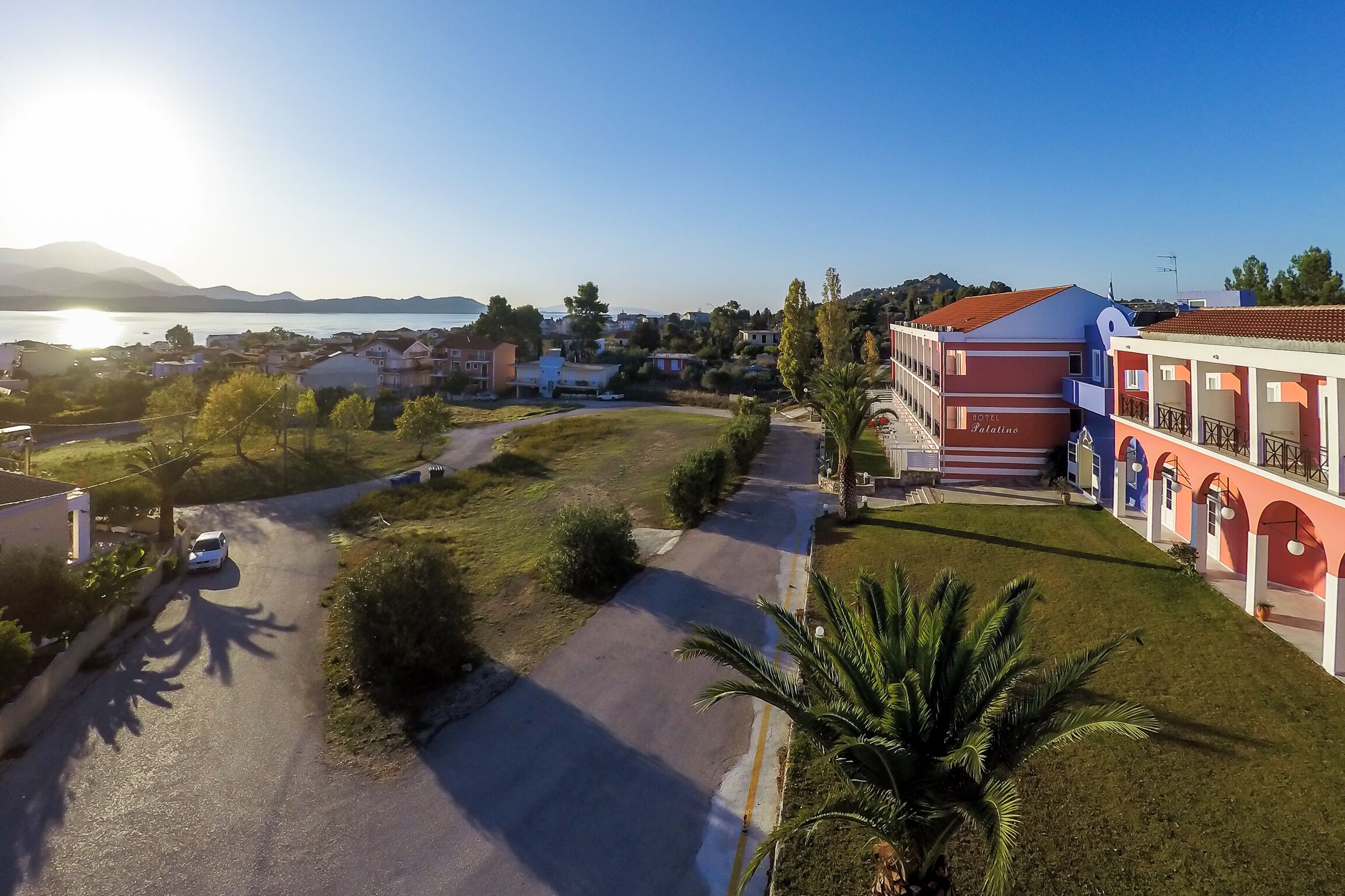 Un hotel costero con un camino pavimentado, una zona de piscina y vistas al mar.