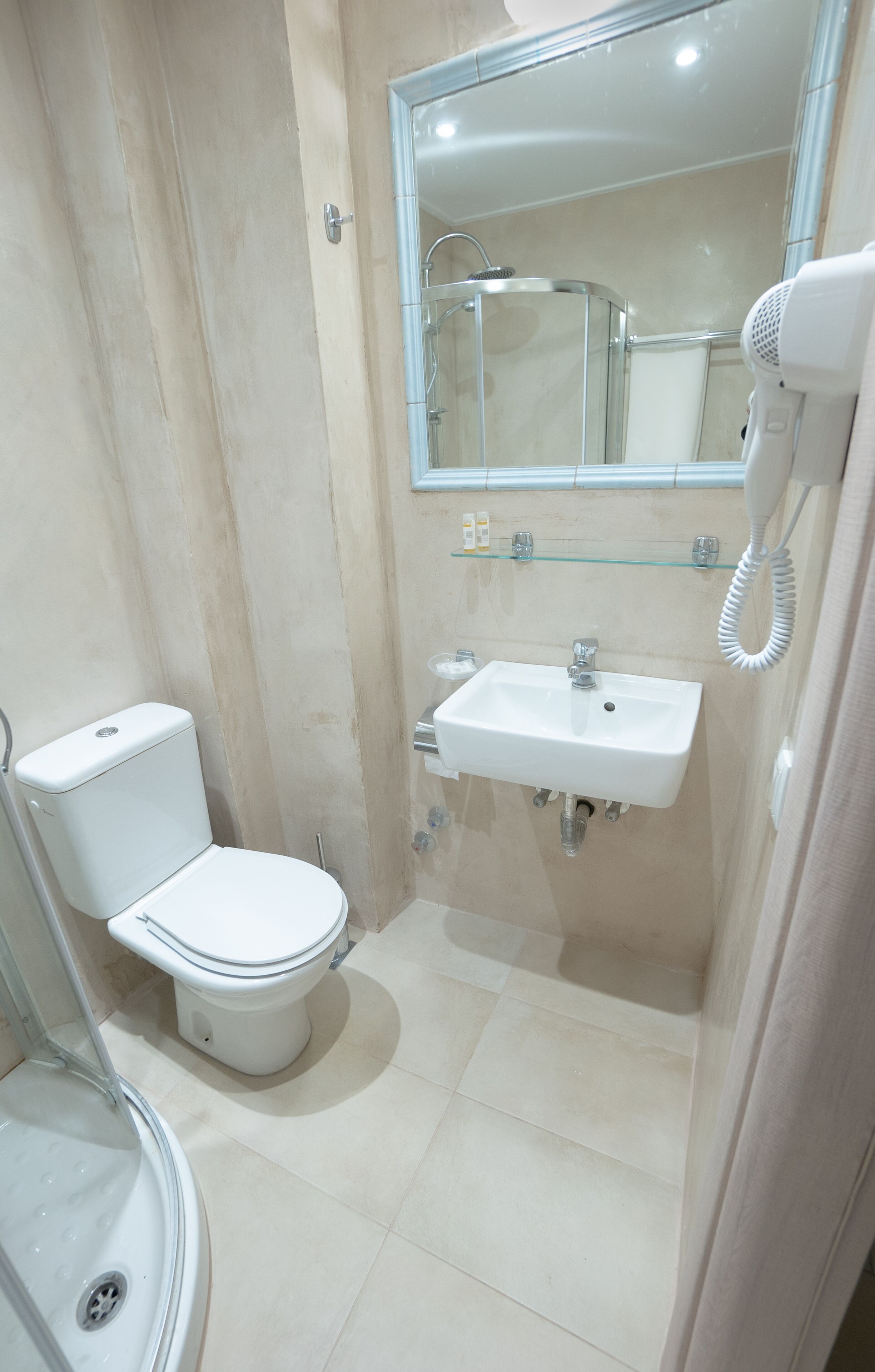 Een kleine badkamer met toilet, wastafel en douche.