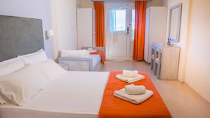 Habitación de hotel con una cama grande, una cama más pequeña, un escritorio y un espejo.