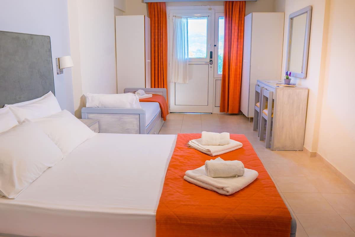 A hotel room with a large bed, a smaller bed, a desk, and a mirror.