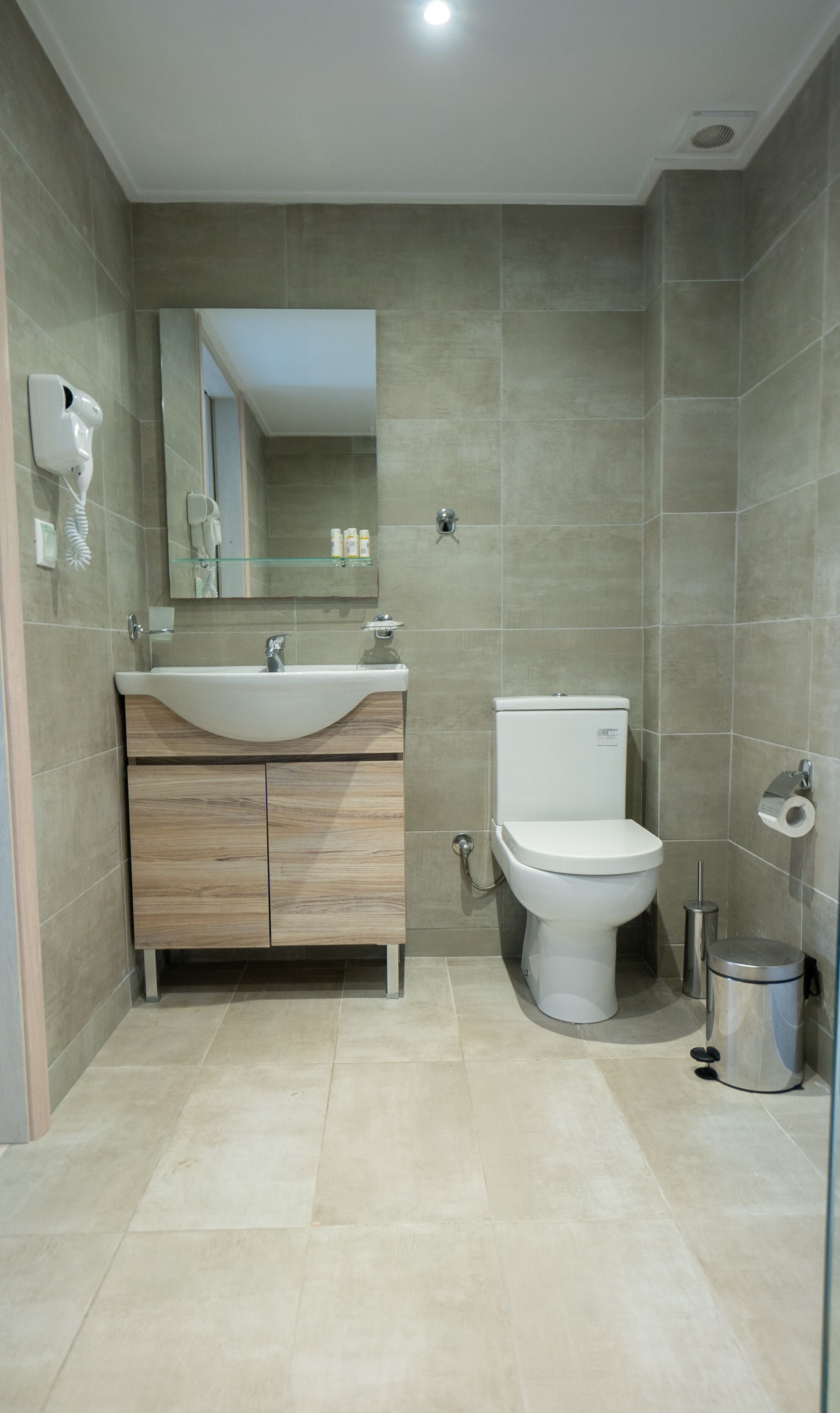 A modern bathroom with a sink, vanity, toilet, and a mirror.