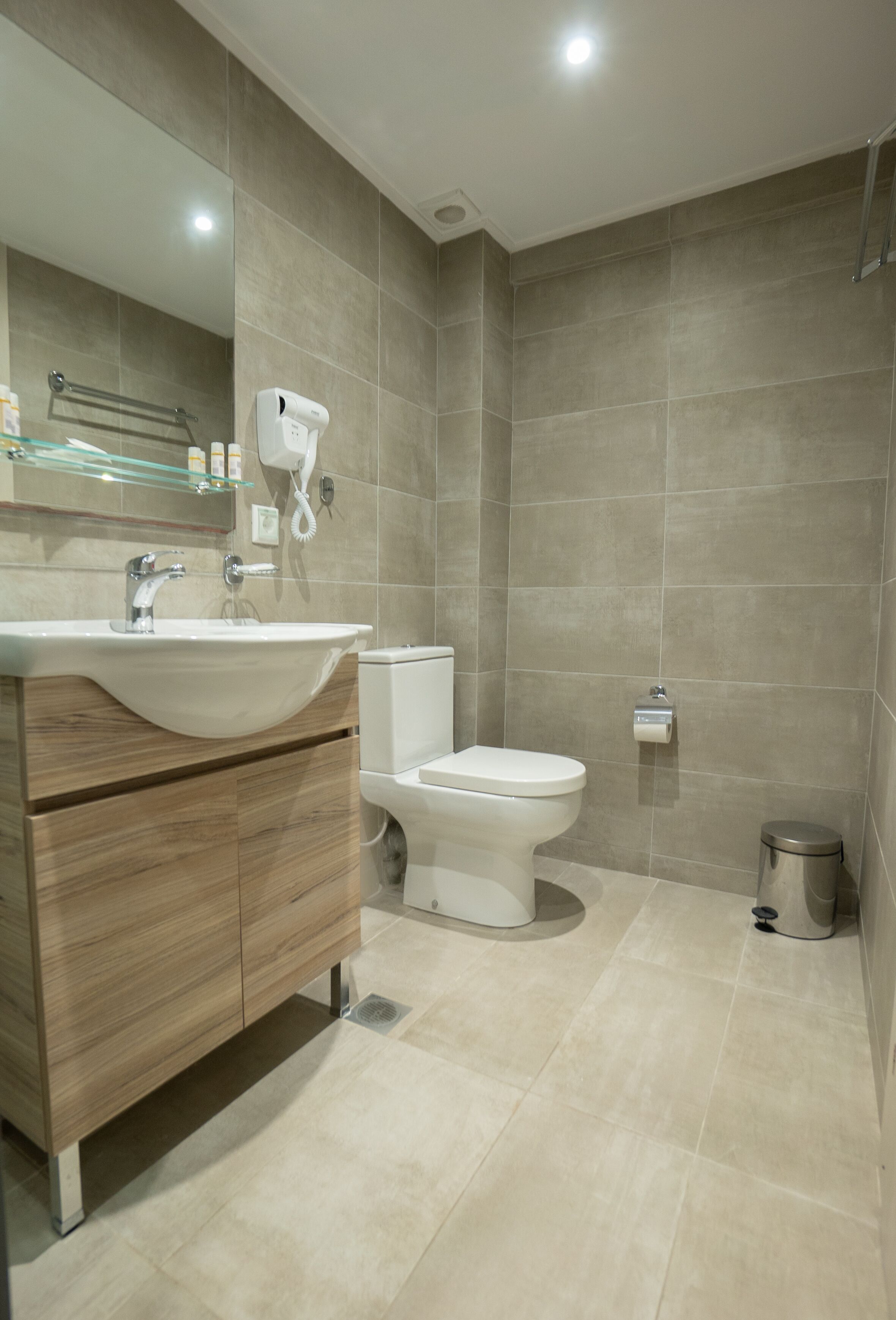 Un bagno moderno con lavandino, specchio, servizi igienici e cestino.