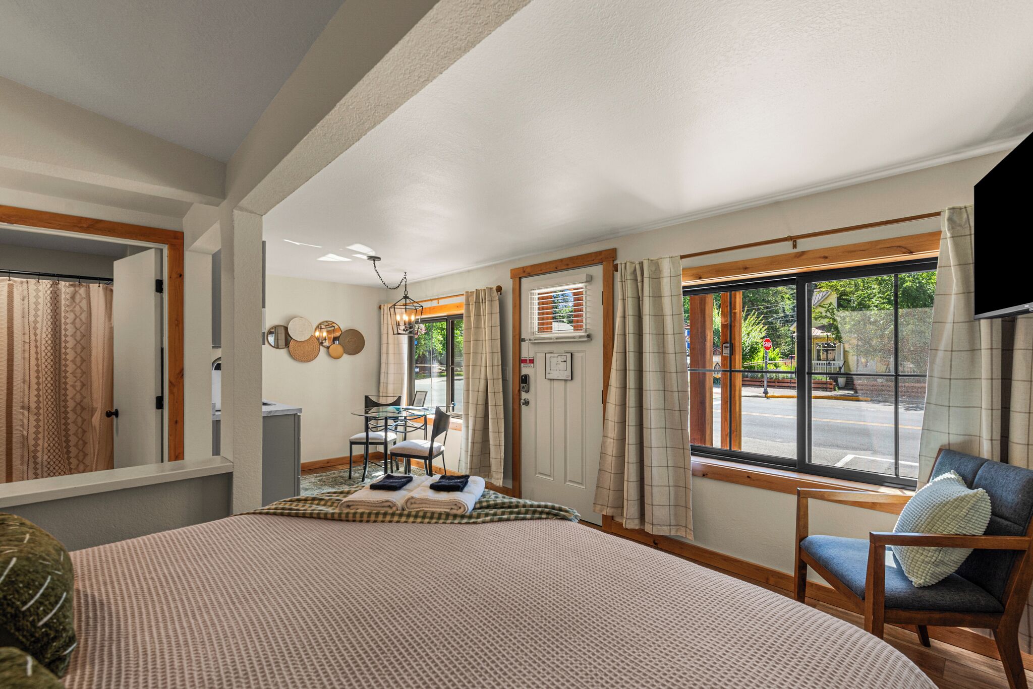 A hotel room with a bed, a chair, a table, and a window with curtains.