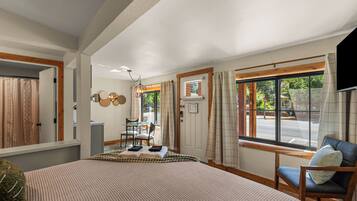 A hotel room with a bed, a chair, a table, and a window with curtains.
