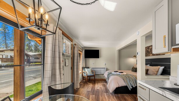 Una moderna camera d'albergo con una grande finestra, un letto, una scrivania e un angolo cottura.