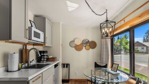 Una cucina compatta con forno a microonde, macchina del caffè e zona pranzo con tavolo e sedie in vetro.