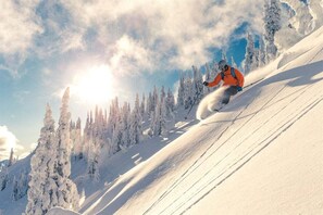 A snowy mountain slope with a skier in motion.