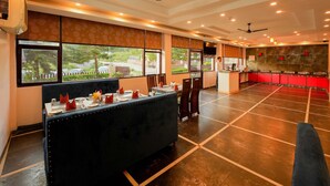 A restaurant with a long counter, multiple tables, and a view of the outdoors. - Hotel 360 By D'Polo Dharamshala (Dharamshala)