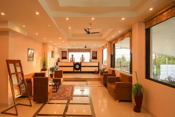 Un hall de hotel con mostrador de recepción, zona de estar y amplios ventanales con vistas.