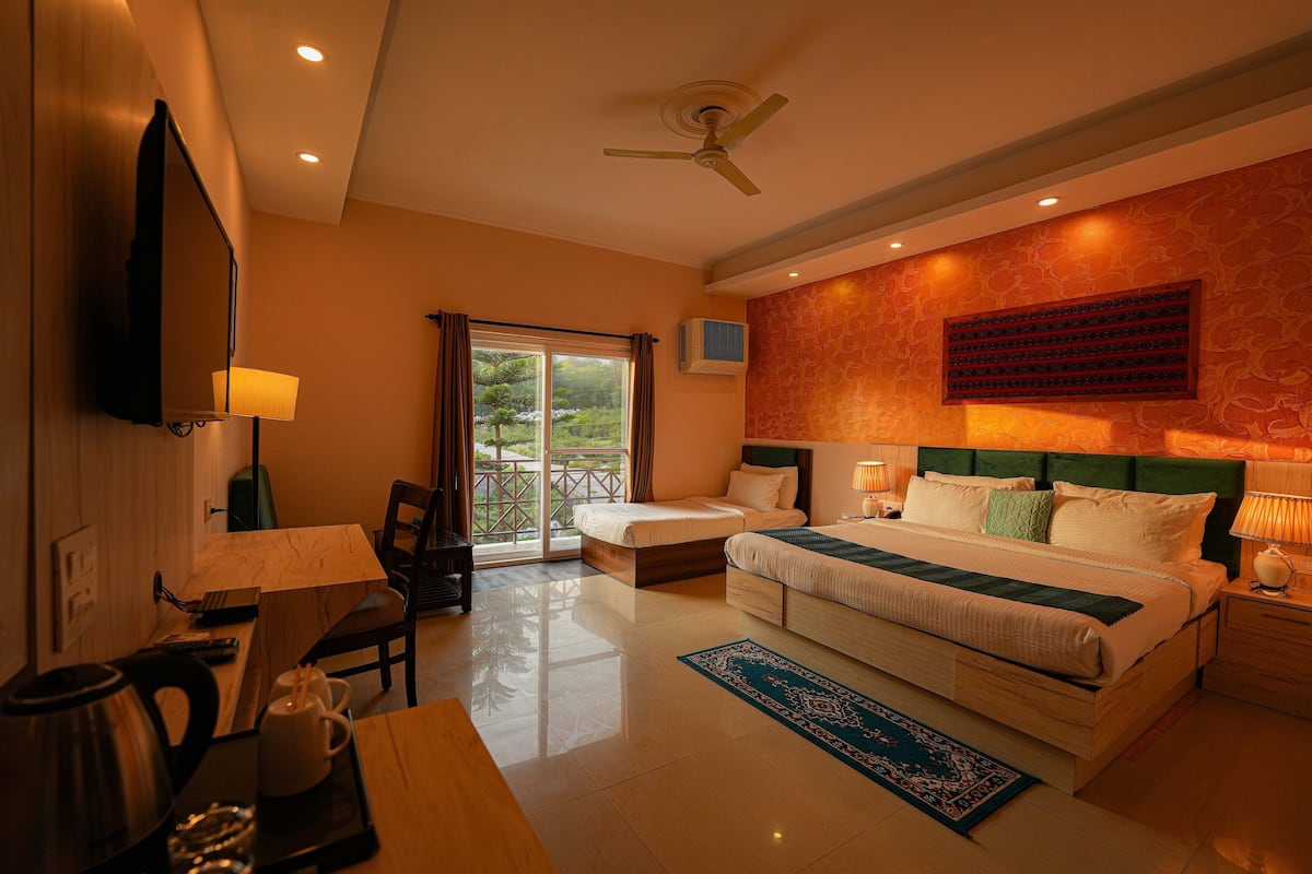 A hotel room with a bed, a desk, a chair, a TV, and a window with curtains.