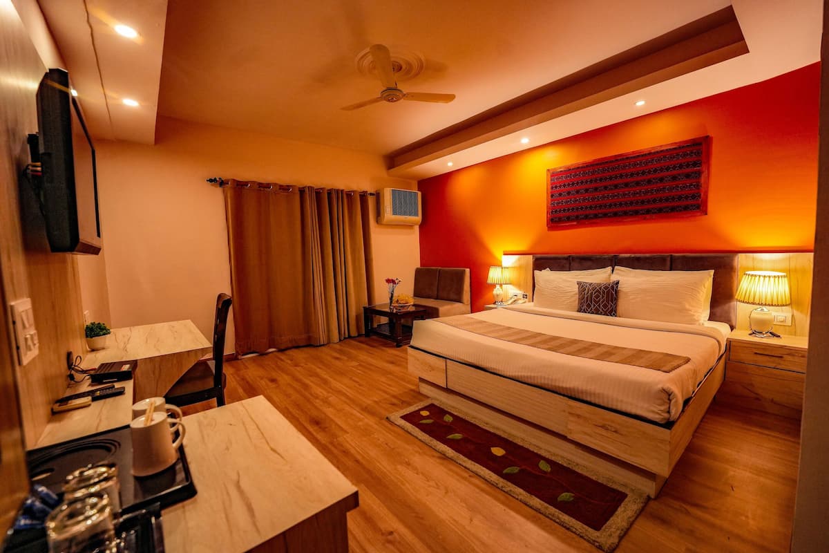 A hotel room with a bed, bedside tables, a desk with a chair, a TV, and a ceiling fan.