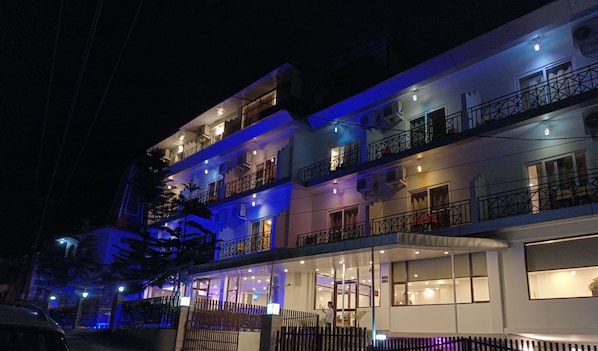 Un hotel boutique de varios pisos con entrada cubierta y balcones en cada planta.