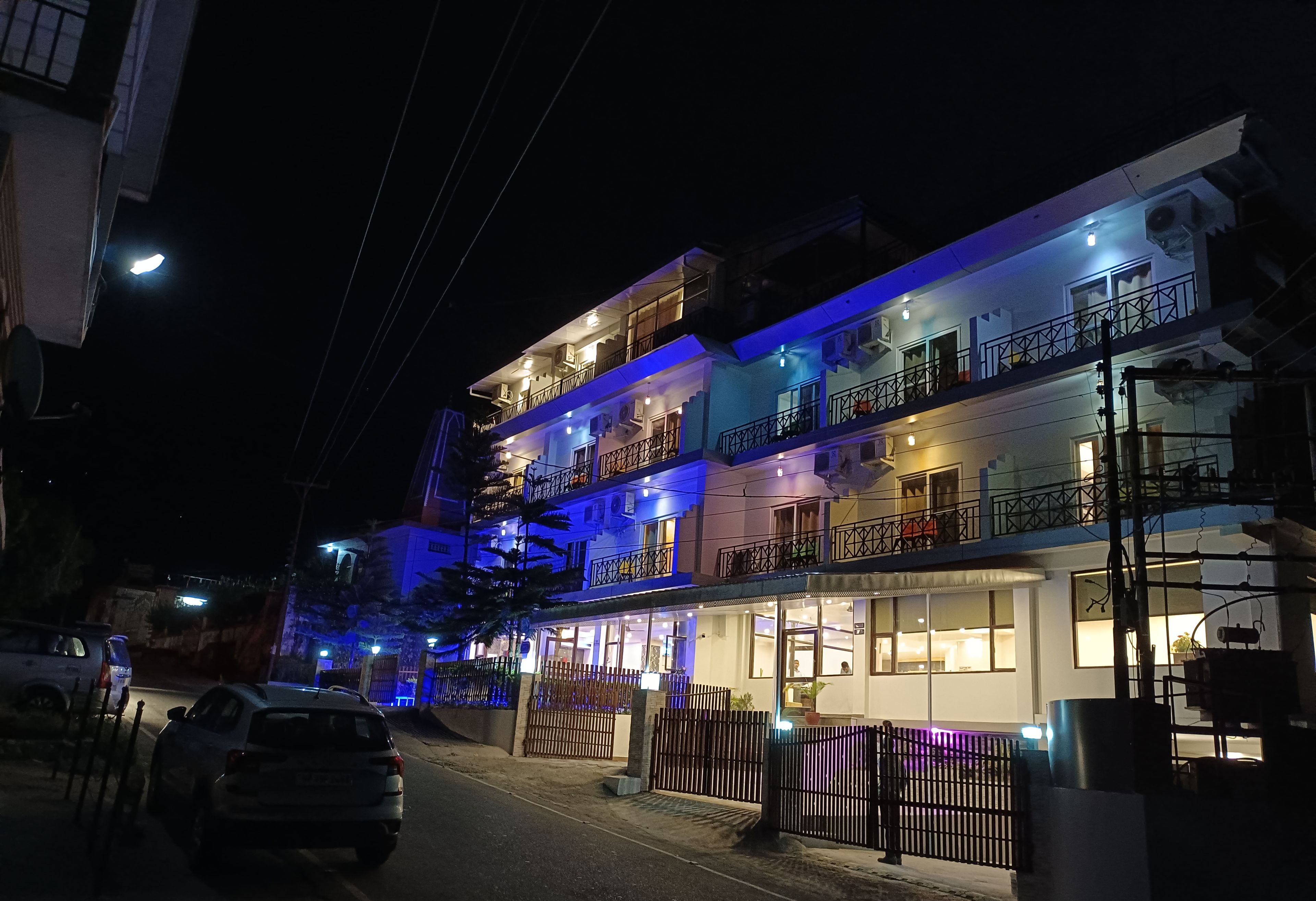 Un hôtel-boutique à plusieurs étages, doté de balcons et d’une entrée bien éclairée.