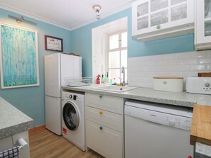 Une cuisine compacte équipée d’un lave-linge, d’un lave-vaisselle et d’un petit plan de travail.