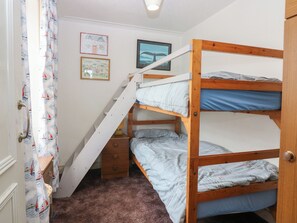 Une chambre avec un lit superposé, un petit bureau, une chaise et une fenêtre donnant sur la mer.