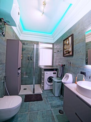 A modern bathroom with a shower, toilet, washing machine, and sink. - Luxury Suite | La Gomera Deluxe. 70 sqm, large Terrasse, max. 3 people (La Calera / Valle Gran Rey)