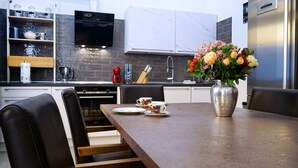 Uma cozinha moderna com uma mesa de jantar, cadeiras, um vaso com flores e uma máquina de café.