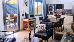 Uma sala de estar moderna com área de jantar, cozinha com televisão e varanda com vista.