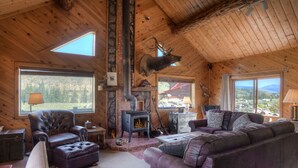 A cozy cabin interior with a fireplace, leather furniture, and large windows offering scenic views. - Rustic Log Cabin - Close to Creede - Picturesque Views (Creede)