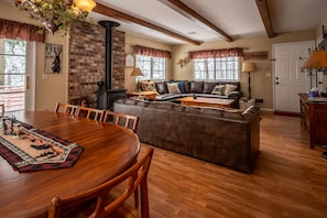 Cozy living space with a round dining table and comfortable seating area featuring a leather sofa and wood-burning stove.