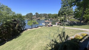 A lakeside property with a well-maintained lawn, dock, and small buildings, likely for recreational use. - Dockside Daze-Prime Waterfront Loc w/ Amazing View, Firepit, Tiki Bar, Lrg Dock (Moneta)