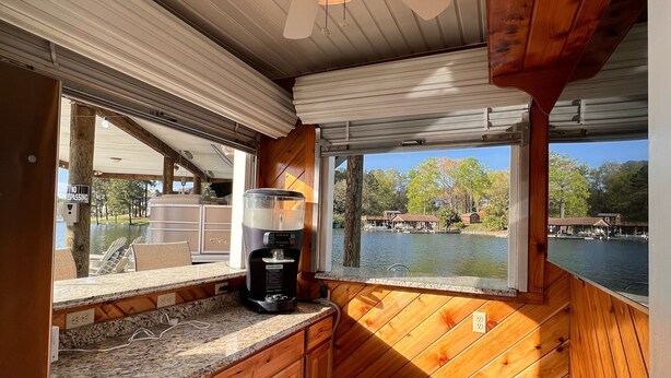 A compact kitchen with wooden cabinets, a granite countertop, a coffee maker, and a view of a lake. - Dockside Daze-Prime Waterfront Loc w/ Amazing View, Firepit, Tiki Bar, Lrg Dock (Moneta)