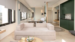 Een moderne woonkamer met een beige bank, een glazen salontafel en een eethoek met een tafel en stoelen.