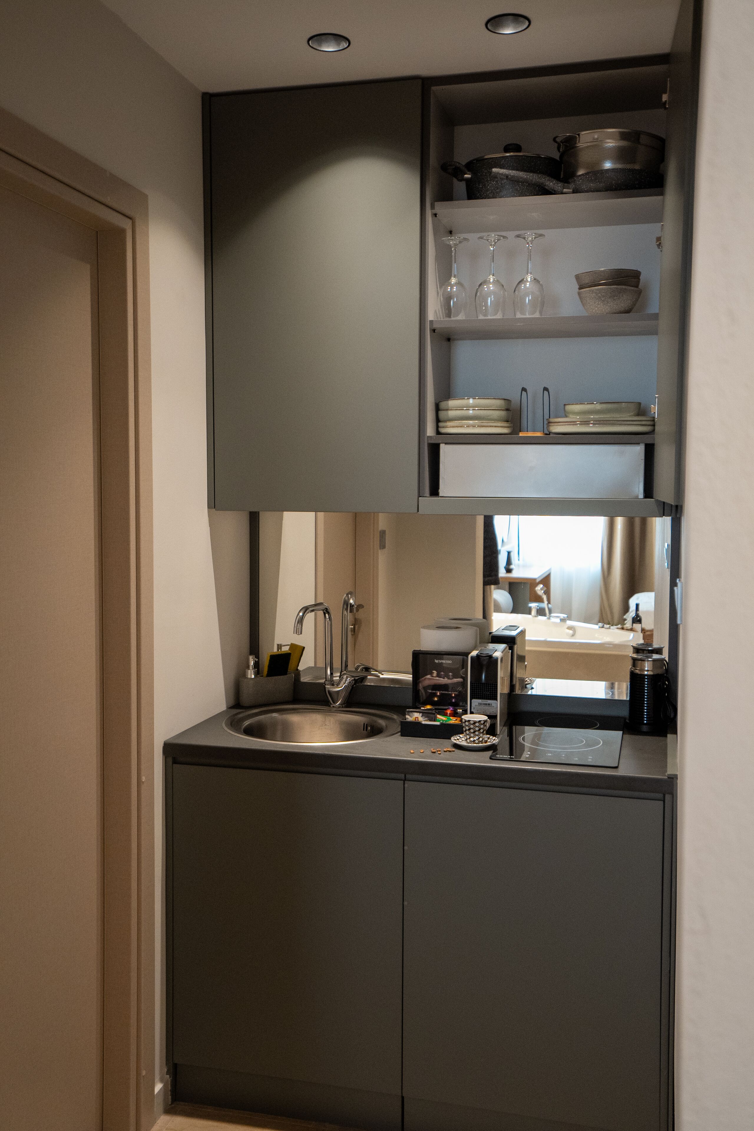 A compact kitchen with a sink, a coffee machine, and a microwave.