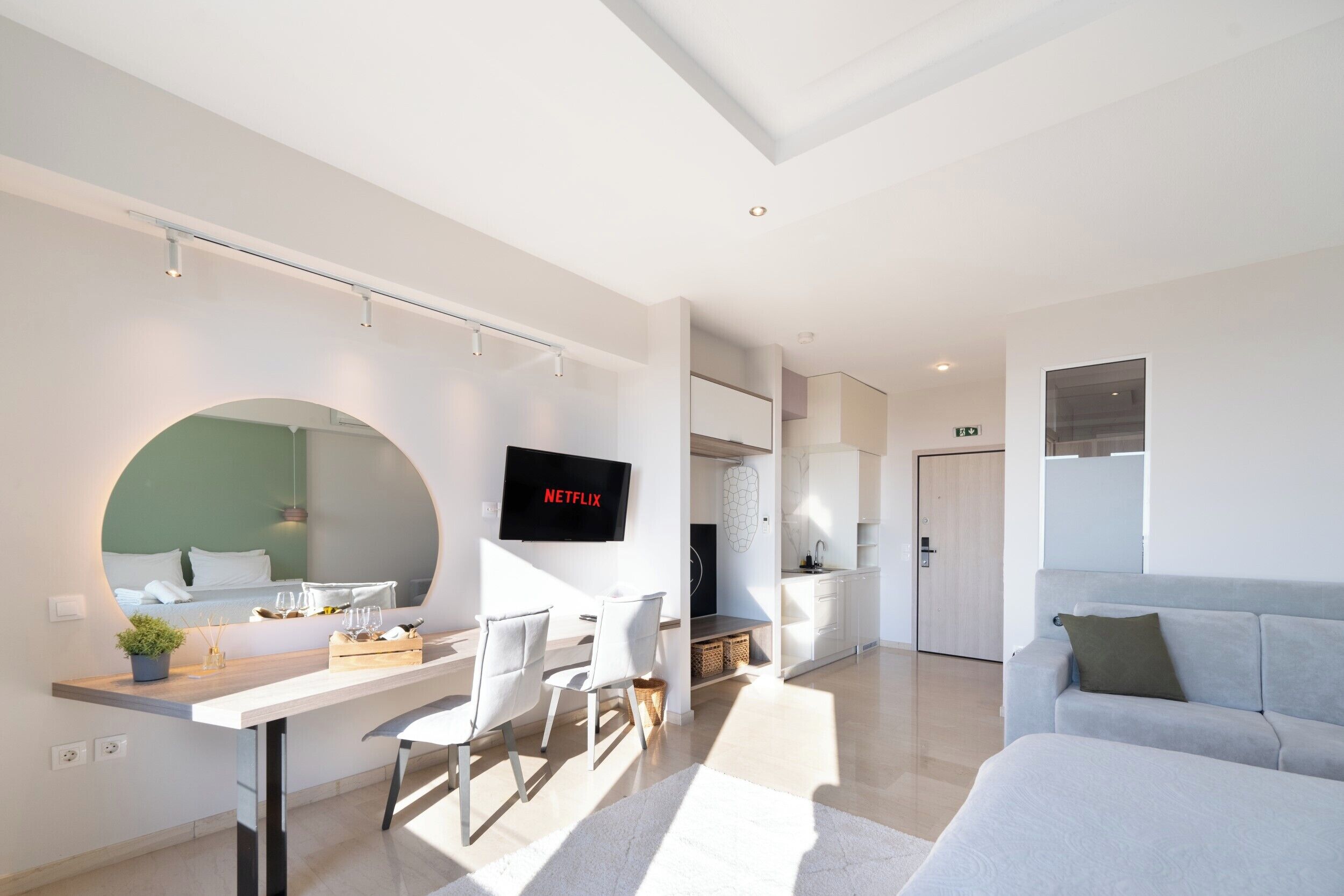Una sala de estar moderna con comedor, televisor montado en la pared y sofá.