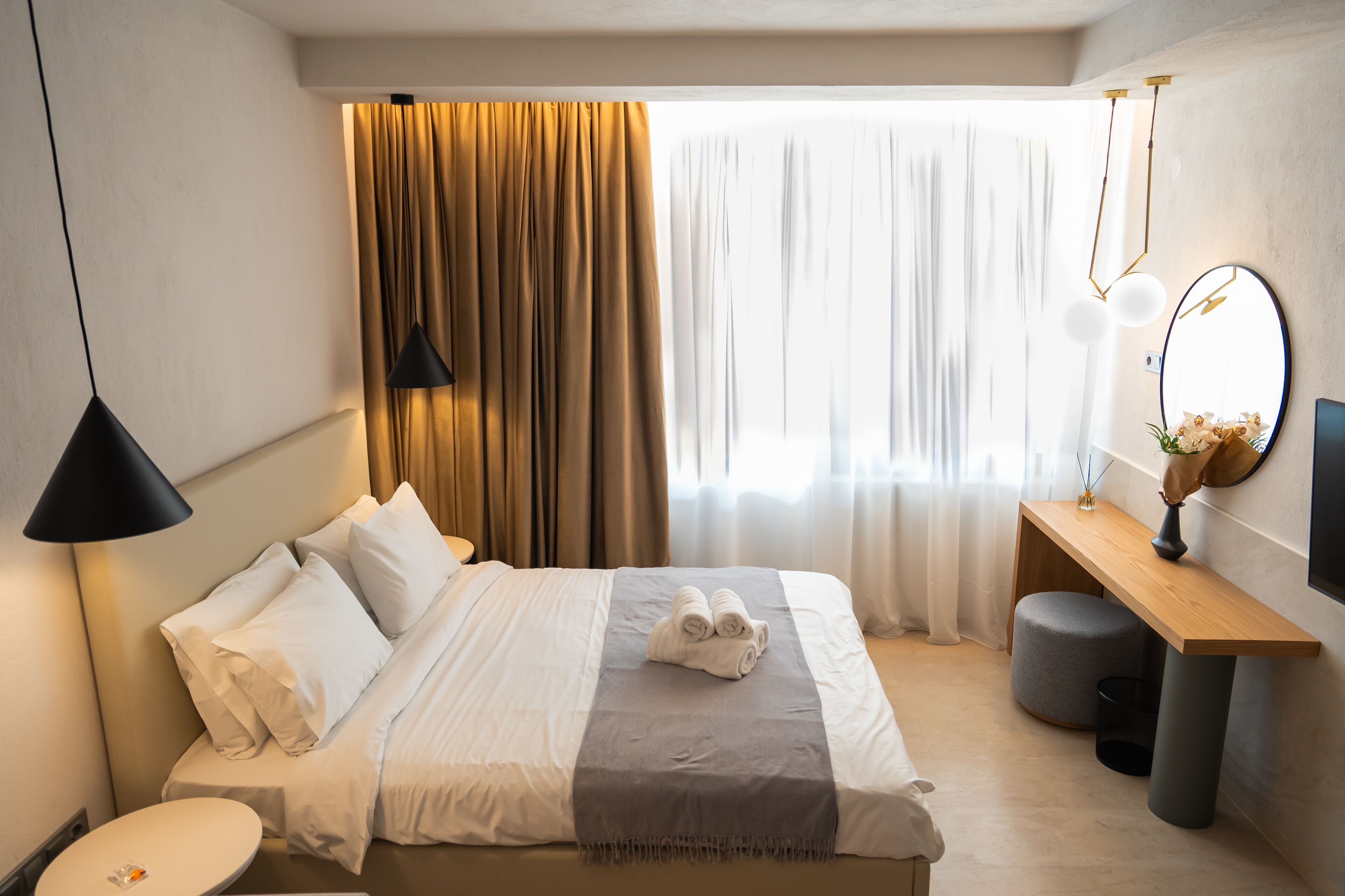 A hotel room with a bed, bedside table, and a mirror.
