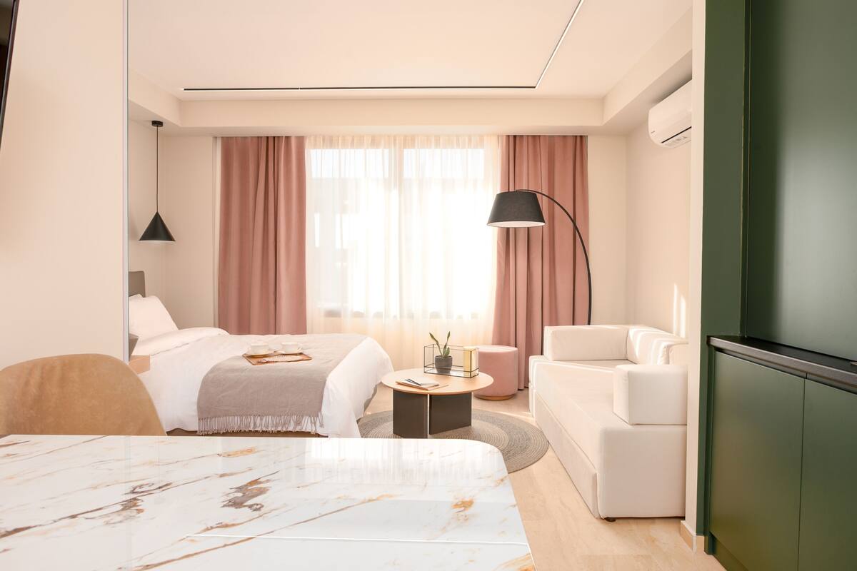 Een moderne hotelkamer met een bed, een slaapbank, een salontafel en een bureau.