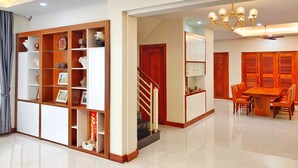 Amplia sala de estar con una estantería de madera, una mesa de comedor con sillas y una escalera que sube a otro nivel.