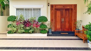 Una casa moderna con puerta de madera, entrada con baldosas y varios maceteros.