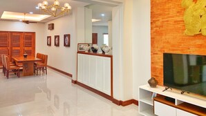 Una sala de estar moderna con televisión, muebles de madera y una pared de ladrillo decorativa.