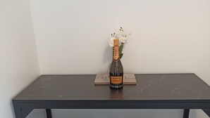 A dark wooden table with a bottle of Canti Prosecco and a small white flower arrangement.