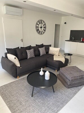 A modern living room with a sectional sofa, a round coffee table, and a grey rug.