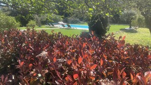 A pool area with lounge chairs and a well-maintained lawn. - MAISON BAMBOU (Le Plan-de-la-Tour)