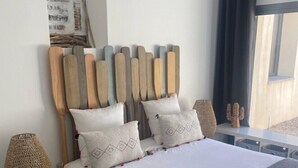 A modern bedroom with a large bed, wooden headboard, and decorative pillows. - MAISON BAMBOU (Le Plan-de-la-Tour)