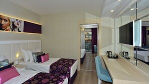 Una habitación de hotel con dos camas, un escritorio, un televisor y vista a la ciudad.