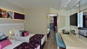 A hotel room with two beds, a desk, a TV, and a view of the city.