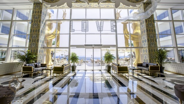 Un vestíbulo espacioso con piso a cuadros, ventanas grandes y vista a la playa.