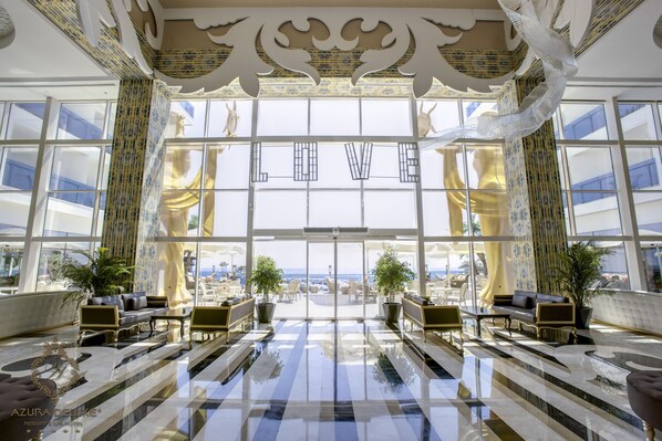 A spacious lobby with a checkered floor, large windows, and a view of the beach.
