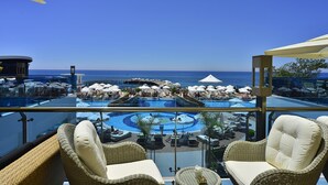 Zona de piscina en la azotea con sillones de descanso y sombrillas, con vistas al océano.