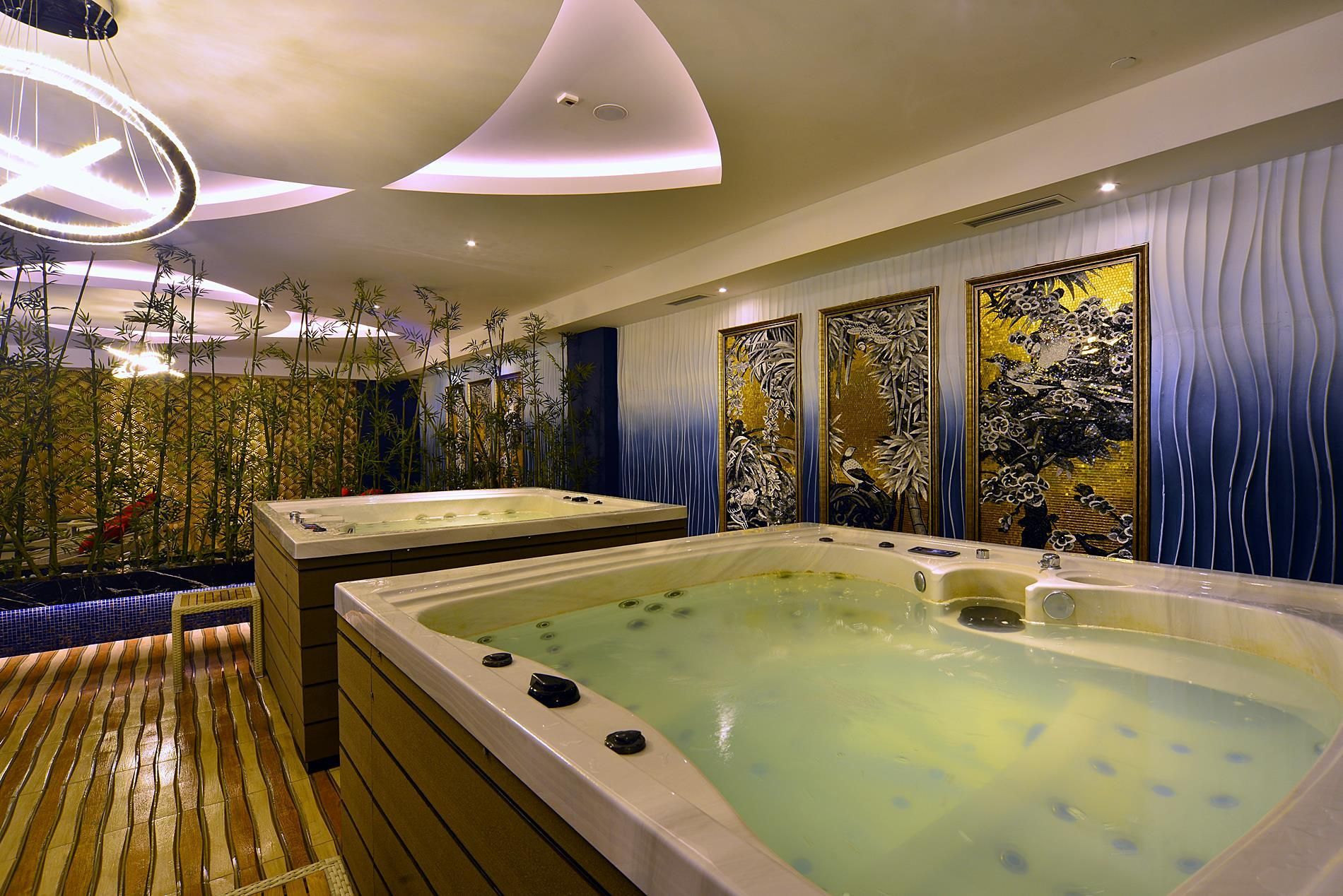 Ett spa-rum med ett stort bubbelbad, trägolv och dekorativa väggpaneler.
