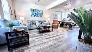 A spacious living area with a high ceiling, a ceiling fan, and a dining area with a table and chairs. - Condo w/3 Rooms, Heated Pool, and Close to Beach! (Corpus Christi)