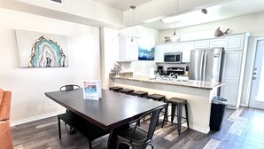A modern kitchen with a central island, white cabinetry, and stainless steel appliances. - Condo w/3 Rooms, Heated Pool, and Close to Beach! (Corpus Christi)
